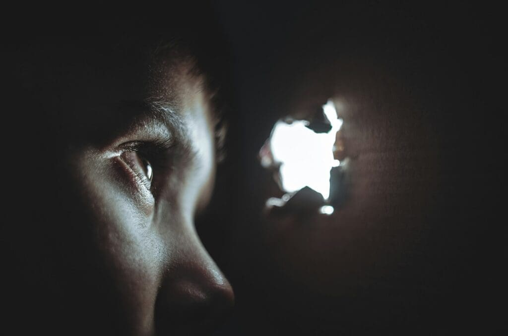 Person looking through a peephole, symbolizing AI scrutiny for performance and security.